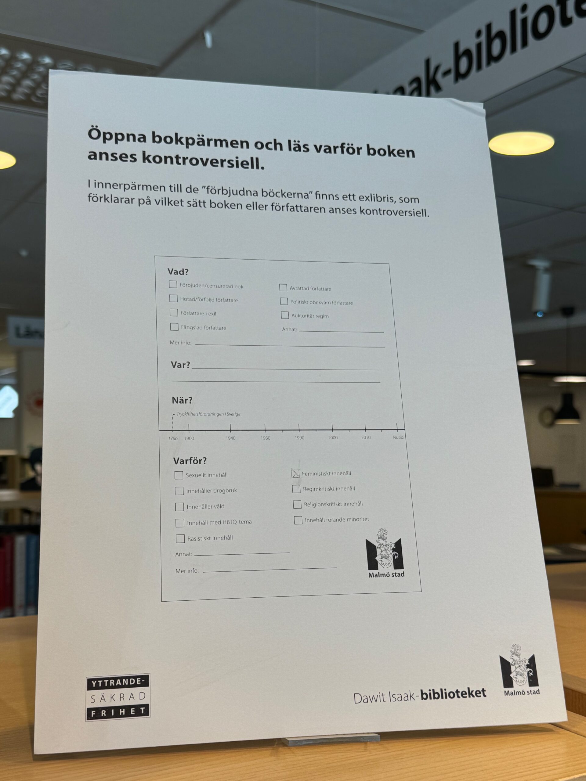 Skylt vid Dawit Isaak-biblioteket i Malmö, skylten förklarar hur varje bok har en lapp på insidan som berättar mer om varför boken motverkats.